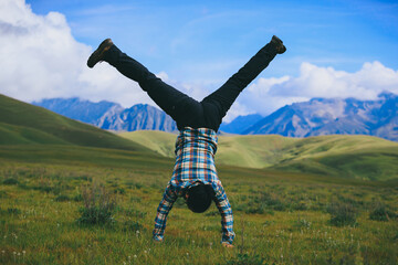 Woman hiker doing a handstand on high altitude mountain top grassland