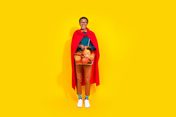 Full size photo of nice elegant young man hold halloween pumpkin shop basket isolated on yellow color background