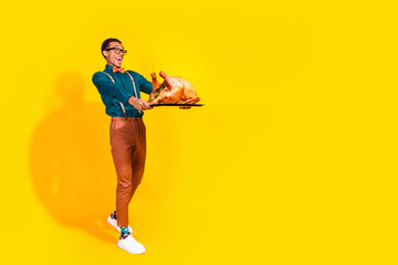 Photo of excited guy hold turkey for thanksgiving day enjoying walk isolated yellow color background