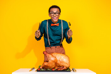 Photo of excited guy hold cutlery lick lips feel hunger eating thanksgiving day turkey isolated yellow color background