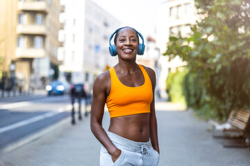 Happy woman listening to music with headphones while exercising in the city