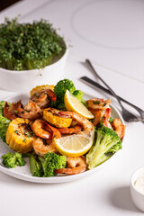 Shrimp and vegetables cooked in the oven for a healthy lunch on a white table