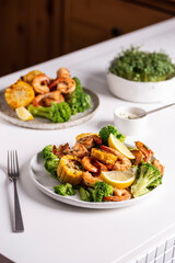 Shrimp and vegetables cooked in the oven for a healthy lunch on a white table