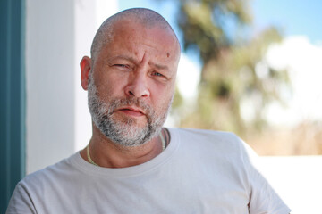 Portrait of a handsome 50 years old man with unshaven hair in a white t-shirt