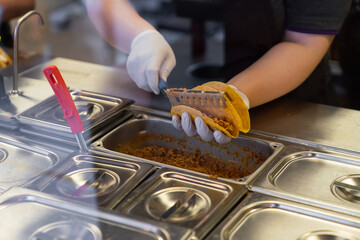 Worker preparing Mexican tacos on food counter in fast food restaurant - Powered by Adobe