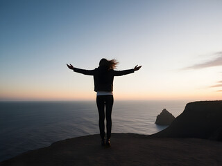 Fototapeta premium a woman stands on a cliff with her arms outstretched.