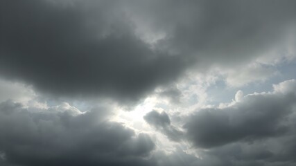 Obraz premium A moody sky with heavy gray clouds and soft sunlight peeking through, creating a dramatic contrast between light and shadow 