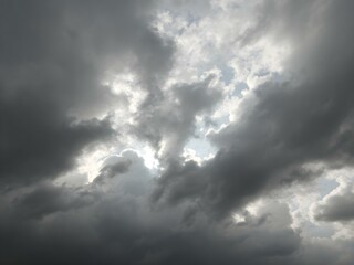 Fototapeta premium A moody sky with heavy gray clouds and soft sunlight peeking through, creating a dramatic contrast between light and shadow 