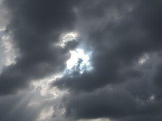 Obraz premium A moody sky with heavy gray clouds and soft sunlight peeking through, creating a dramatic contrast between light and shadow 