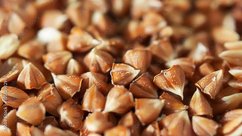 Poster buckwheat groats are scattered, creating a textured background with their distinct triangular shape 