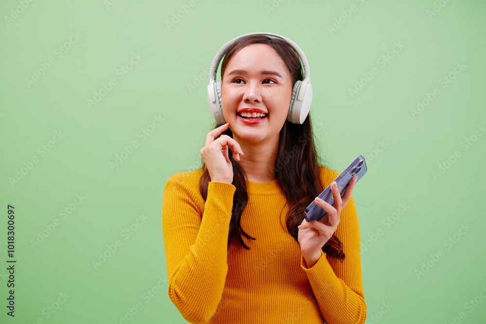 Wall mural young woman smiling with headphones and using smartphone.