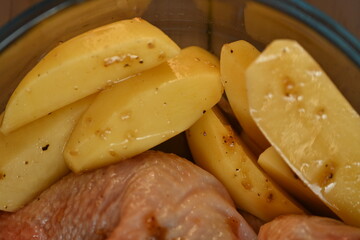 marinated chicken  and potatoes in sauce in a dish before baking, the texture of potatoes and meat cooked for dinner 
