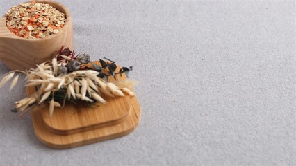 Oats, lentils inside wooden bowl sitting near bamboo coasters decorated with dried plants. Organic textures and soft colors evoke simple, rustic feel.