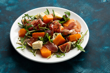 Autumn salad with Jamon blue cheese and figs  roasted butternut pumpkin rocket on white plate food close up