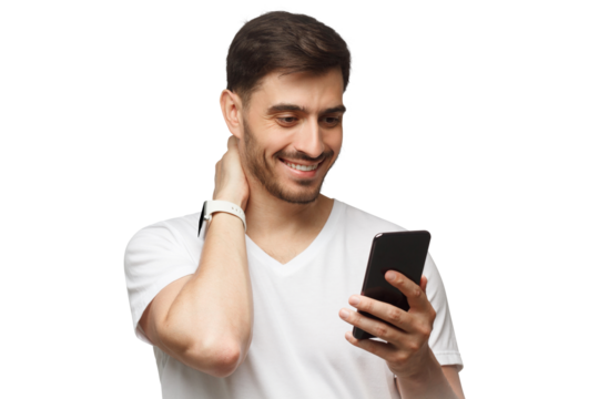 Young man wearing white t-shirt, holding phone in hand and looking at app on screen with smile