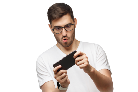 Young man in white t-shirt holding phone with both hands, moving it while playing video game in app, making funny face