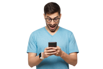 Young handsome guy dressed in blue t-shirt, wearing glasses, holding cellphone in hands, looking at screen with excited face