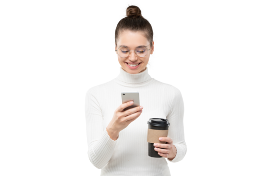 Young attractive woman wearing glasses and white turtleneck sweater, holding phone and paper coffee cup, texting with smile