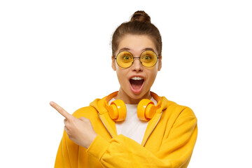Young shocked girl, wearing round glasses and headphones on neck, pointing left