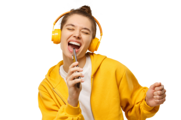 Young woman in yellow hoodie and wireless headphones, singing with closed eyes, holding phone as microphone