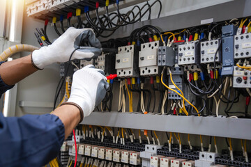 Checking the electrical system, an electrician is using an electric meter to check the electrical system at a control cabinet. for safety
