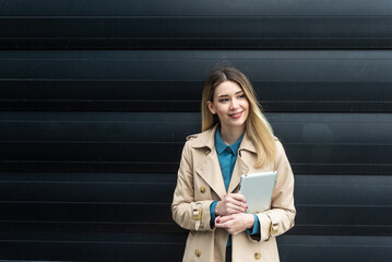 Portrait of young businesswoman standing outside office building. Successful professional office worker, business person against black wall background. Businesspeople professional lifestyle concept