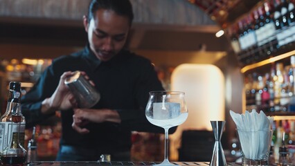 Asian smart bartender shaking mixed cocktail preparing to serve at luxurious counter preparation, making special drink looking at camera fronted view. Special refresh drink nightlife luxury. Vinosity.