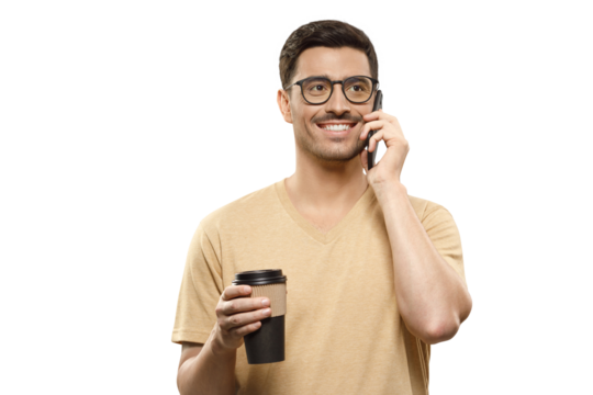 Young handsome businessman in beige t-shirt and glasses, talking on phone with takeaway coffee cup in hands