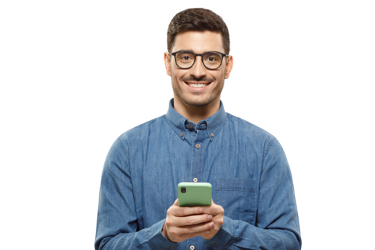 Young modern man in casual blue shirt and trendy glasses, holding phone in hands, exchanging and typing messages to his friends, looking at camera with smile