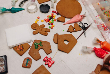 Little girl adding colorful candy on a gingerbread house she is decorating 