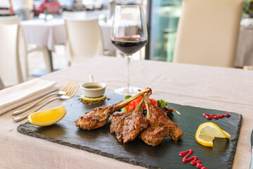 Costolette di agnello cotte sulla brace e servite con insalata di pomodori di contorno e salsa alle erbe