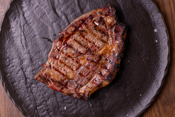 Fetta di carne cotta sulla brace e servita in una braceria in un piatto nero di ardesia