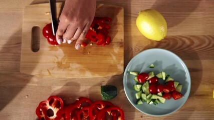 Housewife cooking dinner for family, closeup view from top on woman hands. African American lady cutting vegetables for salad or soup, using chopping board and sharp knife, table top in home kitchen