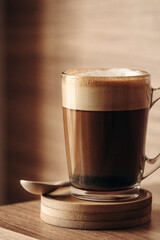 coffee in a cup with foam and spoon on a wooden background