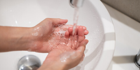 Close-up washing cleaning hand with soap water hygiene in sink faucet in COVID-19 era to prevent infection protection virus, human hand with foam liquid purity routine finger cleanliness healthy