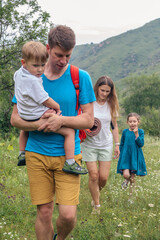 A joyful family happily enjoying a beautiful scenic hike in the breathtaking mountains, accompanied by their children