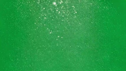 Falling white particles disperse against a green screen backdrop. Ideal for enhancing visual effects, motion graphics, and compositing projects