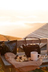 close up of a cup of coffee and a teapot with chocolate for breakfast at sunrise in the mountains