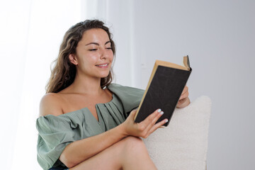Young girl reading an interesting book. Young woman entertains herself by reading a book. She...