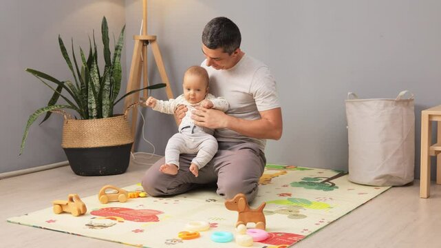 Smiling father testing muscle tone showing care and support during early stages of health and development examining infant&rsquo;s foot and legs for hypotonic
