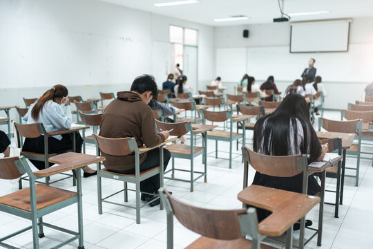 A group of students focuses on their exam papers in a classroom, highlighting the academic testing and learning environment in schools.
