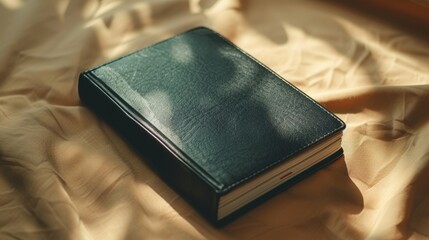 Black Leather-Bound Journal Closed on Beige Fabric, Shadows, and Sunlight Illumination