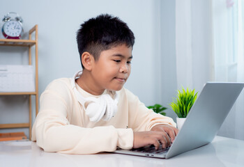 Educational of tech concept, Staying at home, Little Asian boy student using computer laptop learning.  Presenting a modern educational way of life. Virtual internet online class from school teacher.