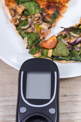 Glucometer for checking sugar level and fresh baked vegetarian pizza. Nutrition during diabetes