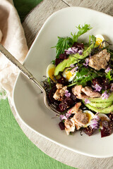 plate with salad with cod liver, avocado and beetroot on a light table