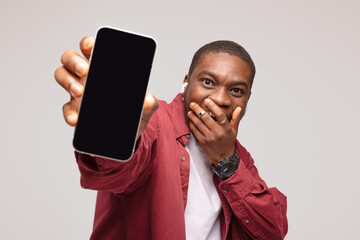 Surprised african young man showing smartphone screen and rejoicing at success, on white background,