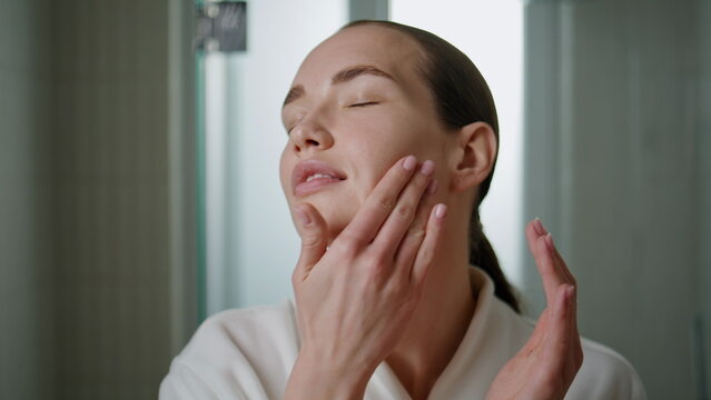 Beauty girl massaging serum on face closeup. Attractive woman applying cream