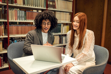 Two students discussing project while working together in the library