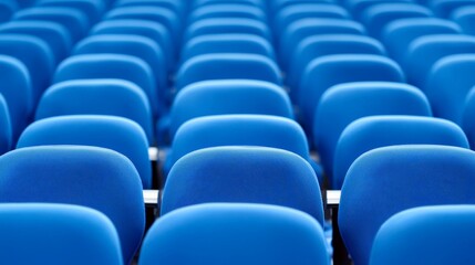 A row of blue conference chairs aligned neatly in an auditorium setting.