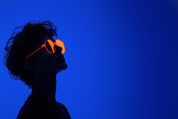 Silhouette with orange glasses on blue background